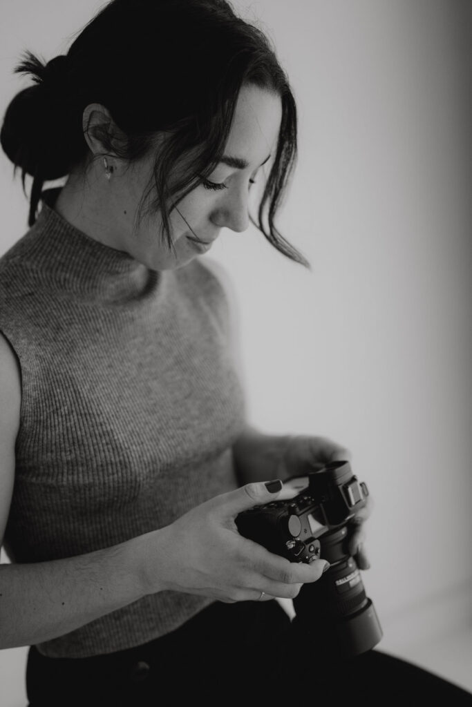 Portrait einer professionellen Hochzeitsfotografin aus Kärnten mit Kamera bei natürlichem Fotoshooting im Tageslichtstudio